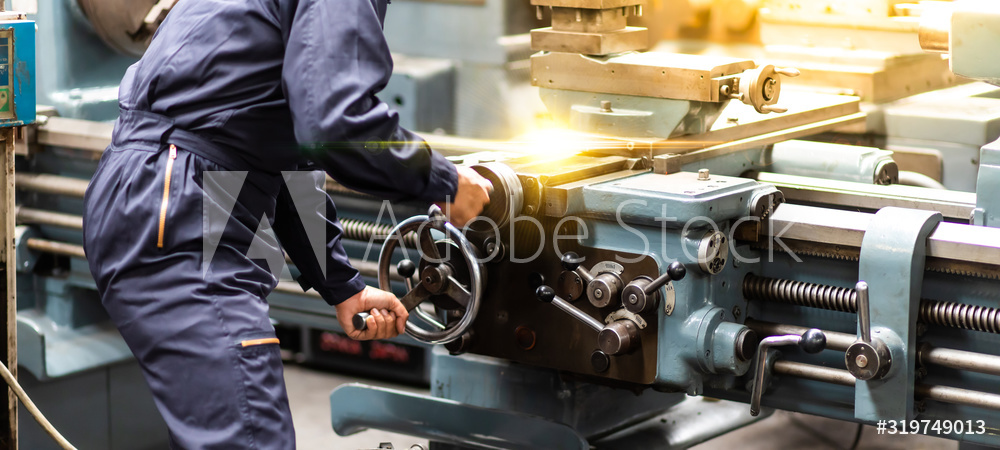 Factory Asian male worker. Asian man Lathe worker in production plant drilling at machine on the factory. Yellow hard hat safety first at mechanic factory.